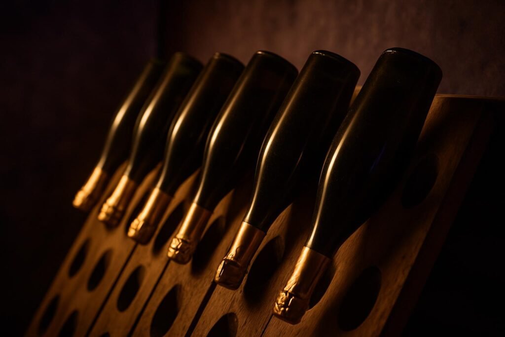 MCC vs Champagne: The Difference, and Which One to Buy 2 Sparkling wine bottles resting neck down in a wooden rack