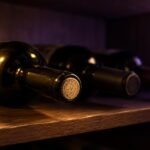 Wine bottles lying on their sides on a dark wardrobe shelf