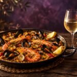 Seafood paella with a glass of white wine and a glass of rosé