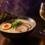 A bowl of ramen next to a glass of white wine